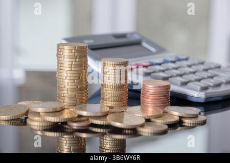 Pièces empilées et une calculatrice avec un fond flou. Banque D'Images