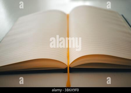 Un nouveau carnet ouvert sur une table blanche avec un ruban marqueur jaune au milieu. Banque D'Images