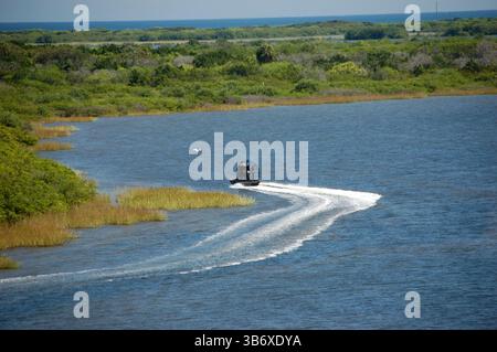 Un hydroglisseur glisse sur les voies navigables près du Kennedy Space Center, entouré de zones humides luxuriantes et offrant une vue imprenable sur l'océan Banque D'Images