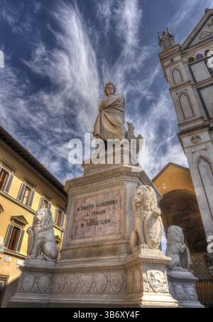 Statue de Dante Alighieri à Florence, en Italie, debout fièrement devant la Basilique di Santa Croce, sous un ciel dramatique avec des nuages sinueux. Banque D'Images