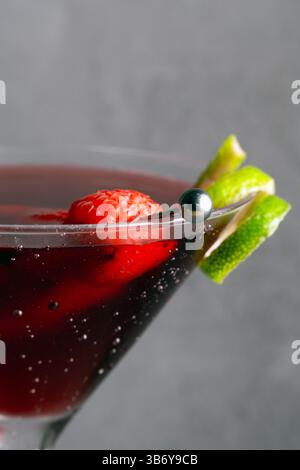 Un verre à martini avec une garniture de citron vert et de framboises. La boisson est servie dans un verre à martini avec une garniture de citron vert et de framboises Banque D'Images
