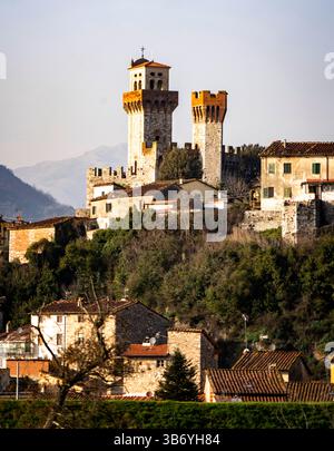 Un château historique avec deux tours proéminentes situé sur une colline, entouré d'une végétation luxuriante et un petit village en contrebas. La scène capture l'essen Banque D'Images