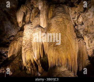 Une vue imprenable sur une formation de grotte avec de grandes stalagmites texturées et stalactites illuminées par un éclairage doux, mettant en valeur la beauté naturelle Banque D'Images
