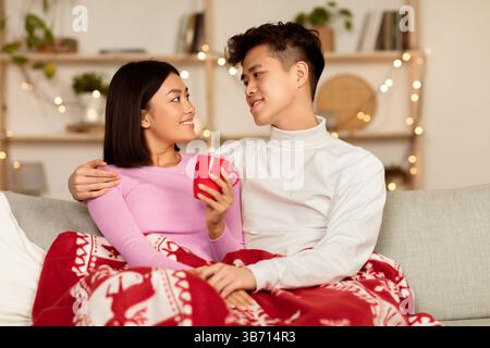 Un couple coréen amoureux se fait un plaisir de boire un café chaud à l'intérieur Banque D'Images