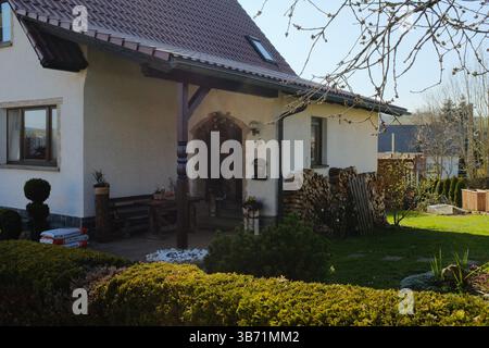 maison de campagne européenne traditionnelle avec toit carrelé porche en bois et jardin entretenu dans un cadre rural printanier. Photo de haute qualité Banque D'Images