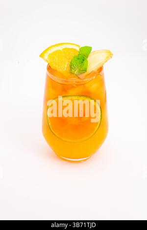 cocktail rafraîchissant aux agrumes oranges avec des tranches de citron et de feuilles de menthe servi dans un verre clair sur de la glace sur fond blanc. Photo de haute qualité Banque D'Images