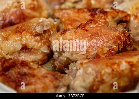 Gros plan incliné de cuisses de poulet parfaitement frites à la croûte dorée profonde. Banque D'Images