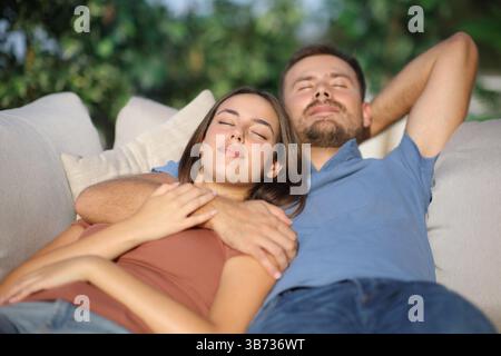 Couple sieste ensemble assis sur un canapé dans une terrasse Banque D'Images