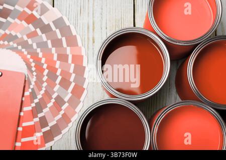 Boîtes avec peinture dans les tons de rouge et palette de couleurs sur fond de bois blanc, vue de dessus Banque D'Images