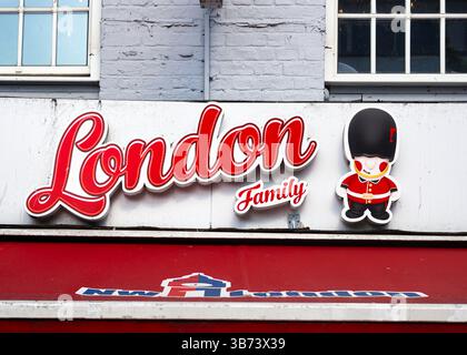 Londres, Royaume-Uni - 28 avril 2025 : un panneau de magasin London Family en lettres rouges et une figure de garde britannique de dessin animé. Banque D'Images