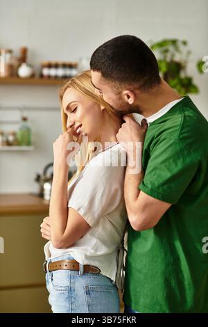 Un couple dévoué partage un moment tendre à la maison, mettant en valeur l'amour et la connexion dans leur cuisine. Banque D'Images