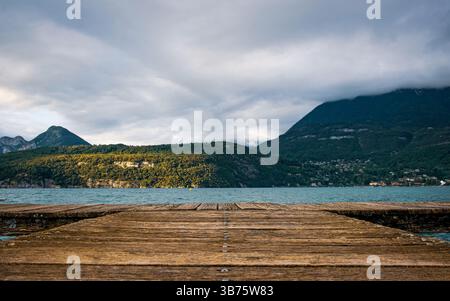 Jetée en bois s'étendant dans le lac d'Annecy avec vue sur la montagne Banque D'Images