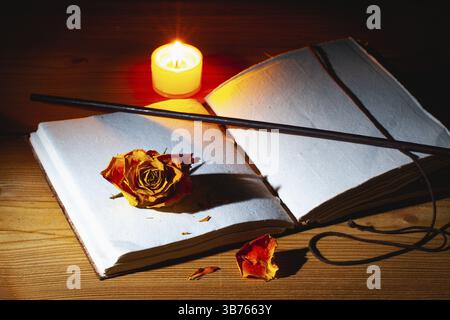 Image de livre magique ouvert, baguette et bougie allumée sur la table en bois dans la pièce sombre Banque D'Images