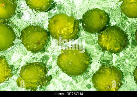 Limes entières fraîches flottant dans l'eau vue de dessus. Banque D'Images