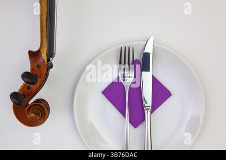 Symphonie du goût. Plaque blanche et vieux violon sur la table en bois blanc.vue de dessus. Image à plat Banque D'Images