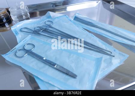 L'image présente divers outils chirurgicaux soigneusement disposés dans un emballage stérile sur un plateau métallique brillant, idéal pour une utilisation dans les salles d'opération et les chirurgies Banque D'Images