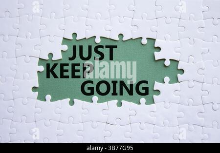 Symbole « continuez à aller ». Puzzle blanc avec des mots juste continuer. Beau fond vert gris. Business and Just Keep Go concept. Copier l'espace. Banque D'Images