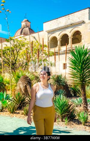 Jeune femme latina souriant brillamment parmi les cactus et les succulentes. Heureux et détendu. Pris dans le jardin ethnobotanique à côté de Santo Domingo à Oaxaca, Banque D'Images