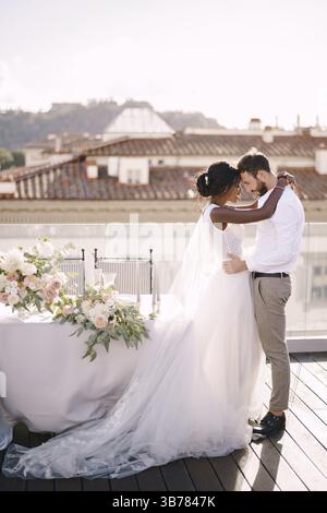 Couple de mariage interracial. Destination mariage beaux-arts à Florence, Italie. Mariée afro-américaine et mariée caucasienne se tiennent près de la table pour une mariée Banque D'Images