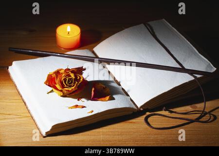 Image de livre magique ouvert, baguette et bougie allumée sur la table en bois dans la pièce sombre Banque D'Images