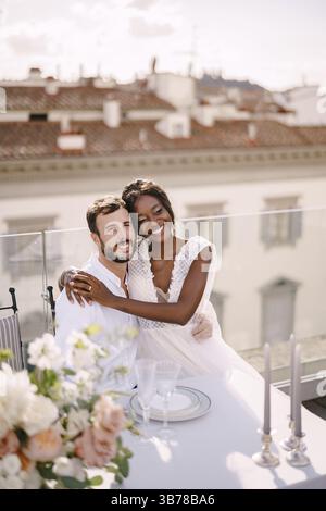 Couple de mariage interracial. Destination mariage beaux-arts à Florence, Italie. Mariée afro-américaine et mariée caucasienne sont assis sur le toit marié Banque D'Images
