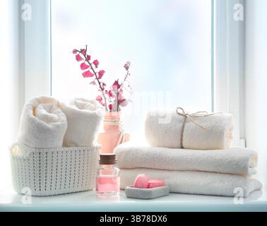 Pile de serviettes pliées, huile essentielle et savon sur le rebord de la fenêtre espace vide de copie.concept de soins du corps, toile de fond de l'hôtel, articles de salle de bains. Banque D'Images