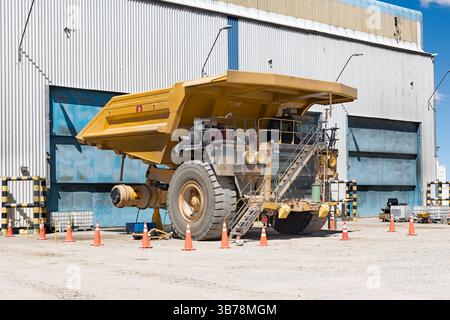 Énorme camion minier dans l'atelier de maintenance d'une exploitation minière, avec l'un de ses pneus géants enlevé. Banque D'Images