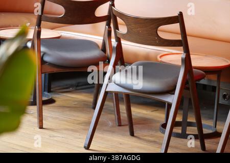 Élégantes chaises en bois disposées autour de petites tables dans un café confortable Banque D'Images
