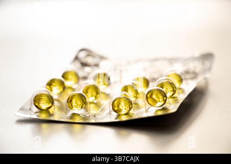 Gélules jaunes dans une plaquette thermoformée sur fond clair, médicaments et vitamines Banque D'Images