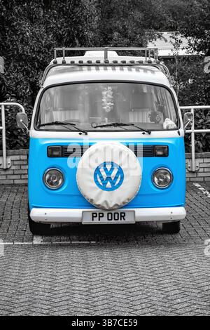 Un camping-car VW vintage représenté en noir et blanc, avec une couleur tache soulignant la teinte bleu vif du véhicule Banque D'Images