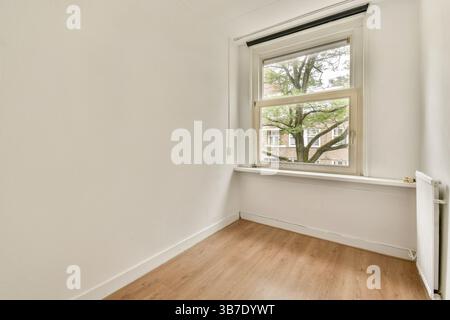 Cette salle spacieuse et bien éclairée dispose d'une grande fenêtre qui invite à la lumière naturelle. Le décor simple met l'accent sur le minimalisme et la tranquillité. Banque D'Images