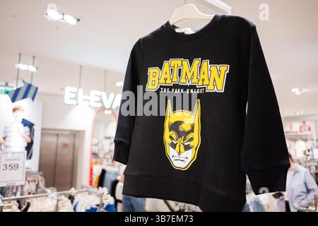 Ivano-Frankivsk, Ukraine - 29 avril 2025 : Sweat-shirt noir élégant avec logo Batman sur cintres dans un cadre de magasin de détail Banque D'Images