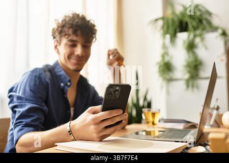 Bel homme aime son temps à l'aide d'un smartphone lors d'une session de travail productive à la maison Banque D'Images