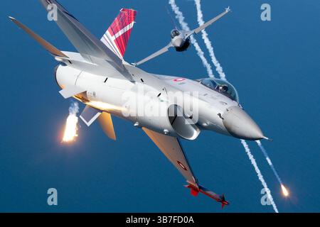 Le General Dynamics F-16AM Fighting Falcon de la Royal Danish Air Force, portant les numéros d'immatriculation E-601 et E-607, est vu dans une démonstration opérationnelle, déployant des fusées éclairantes. Ces fusées éclairantes sont utilisées pour confondre radar ennemi et systèmes infrarouges pendant les scénarios de combat. La queue d'affichage présente l'insigne distinctif de l'armée de l'air danoise. Banque D'Images