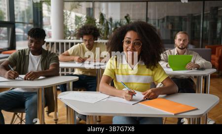Leçon de classe à l'école universitaire collège conférences camarades de classe assis dans la salle de classe femme afro-américaine étudiante femelle demander le problème de l'enseignant Banque D'Images