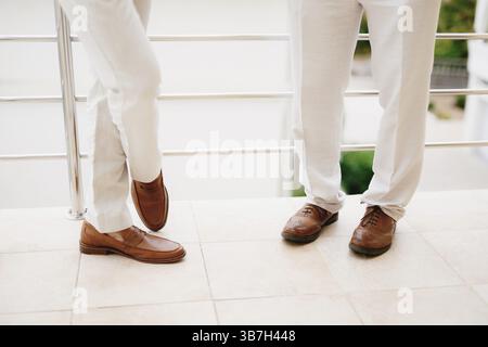 Les jambes de deux hommes debout sur le balcon, gros plan. Le marié et son meilleur homme lors de la préparation de la cérémonie de mariage. . Banque D'Images