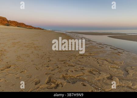 Quelle plage de sable sur l'Atlantique. Paysage photographié au coucher du soleil sur une côte avec des falaises de grès. Marée basse sur la plage jaune de Praia da Falesia près Banque D'Images
