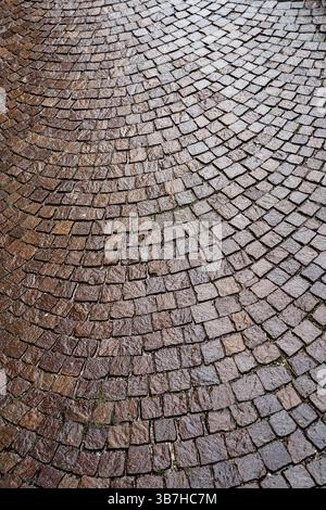 La texture d'une rue pavée brune humide de la pluie. Banque D'Images