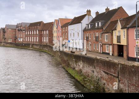 Les gens se promènent le long de la rivière Wensum à Norwich, au Royaume-Uni, en profitant de la vue sur les bâtiments historiques sur la rive. Banque D'Images