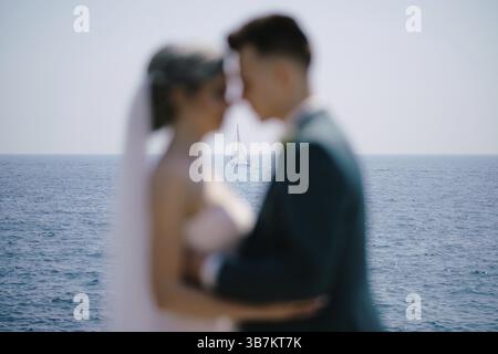 Silhouettes de jeunes mariés embrassés sur le fond d'un yacht à voile blanc en pleine mer. Banque D'Images