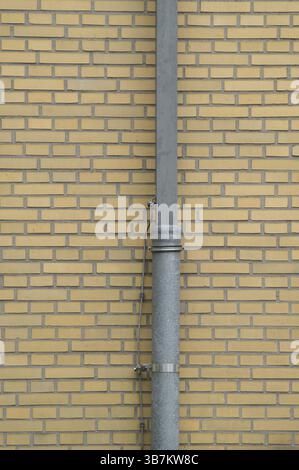 descente en métal attachée à un mur de briques jaunes, créant un détail architectural simple mais visuellement intéressant Banque D'Images