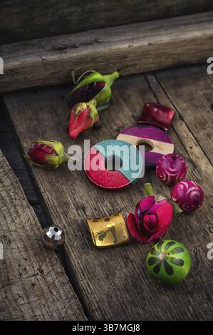 Perles, fil sur fond de boutons de rose sur la planche dans un style vintage Banque D'Images