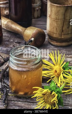 Infusion d'inflorescences et de racines de la plante médicinale Inula sur la table en bois à côté mortier et pilon.photo teintée.Focus sélectif Banque D'Images
