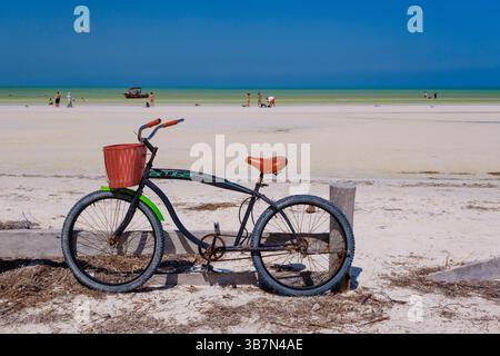 Holbox, Mexique – 10 février 2025 : un vélo de croisière classique avec un panier rouge se dresse sur le sable blanc immaculé d’Isla Holbox, face à la turquoise Banque D'Images