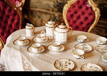 Gros plan sur une table en dentelle blanche avec chaises rouges en peluche. Banque D'Images