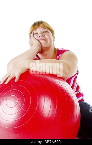 Grosse femme fatiguée avec une grosse balle de gymnastique rouge Banque D'Images