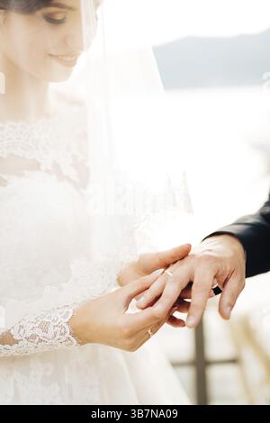 La mariée met l'anneau sur le doigt du marié pendant la cérémonie de mariage. Banque D'Images