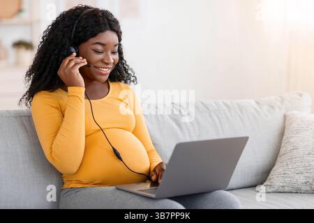 Femme enceinte afro-américaine joyeuse ayant un jeu vidéo à la maison Banque D'Images