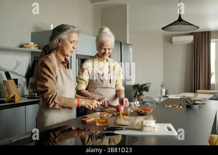Les femmes âgées préparent un repas dans la cuisine moderne Banque D'Images