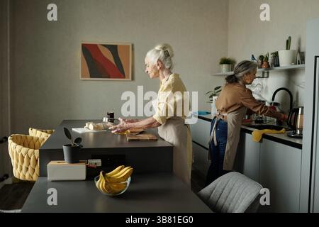 Les femmes âgées préparent un repas dans la cuisine moderne ensemble Banque D'Images